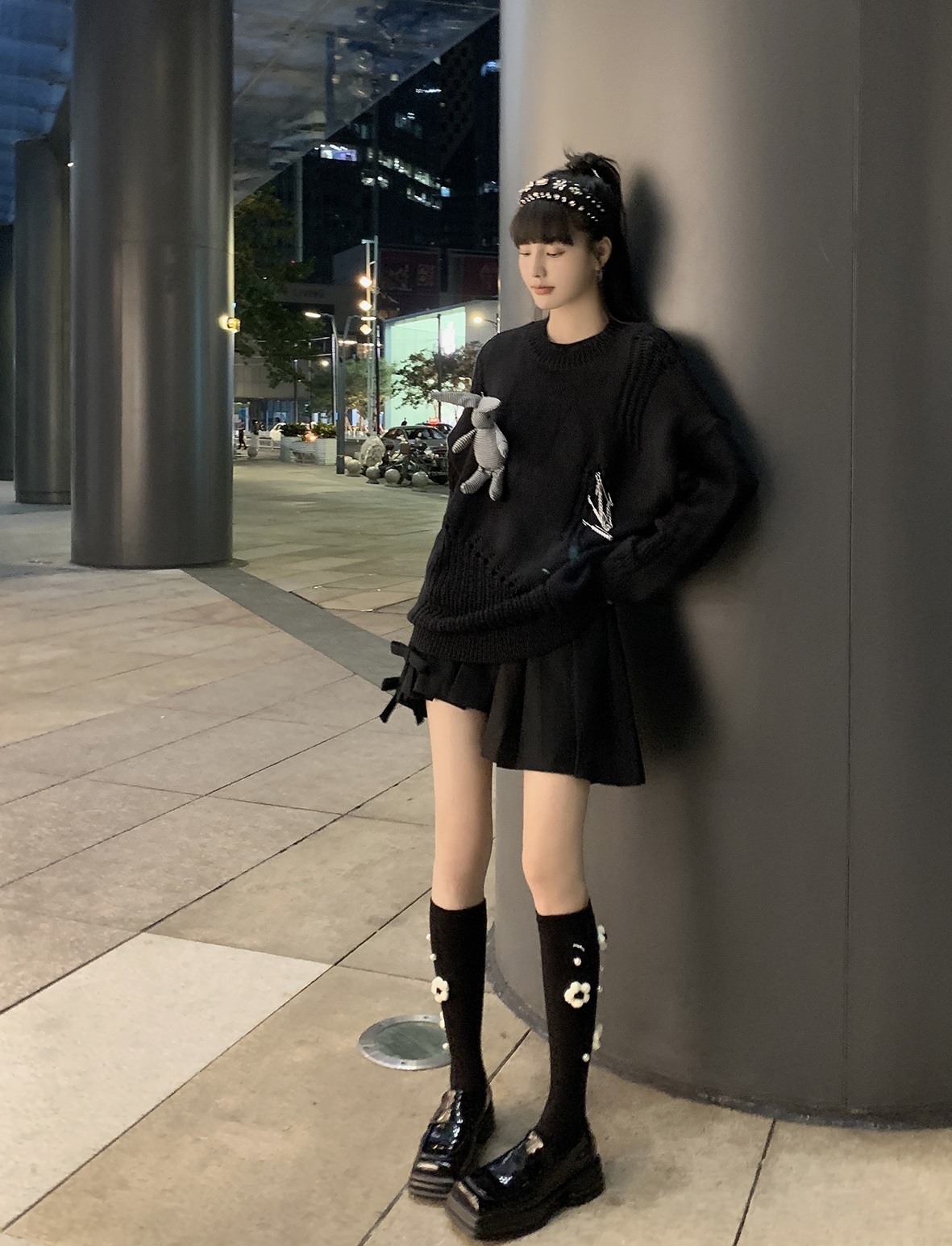 เสื้อกันหนาวไหมพรมสีดำมีแถบสีขาวประดับอกคู่กับกระโปรงจีบสีดำและถุงเท้ายาวสีดำปักลายดอกไม์ดูดีจริงๆ