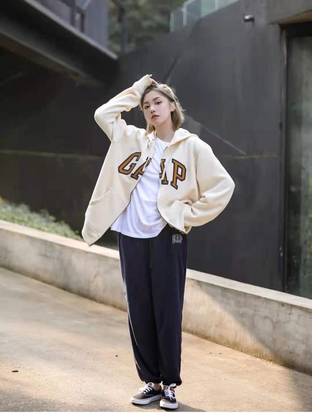 เสื้อกันหนาวมีซิปสีครีมใส่กางเกงวอร์มคู่กับเสื้อยืดสีขาวปล่อยชายเสื้อ