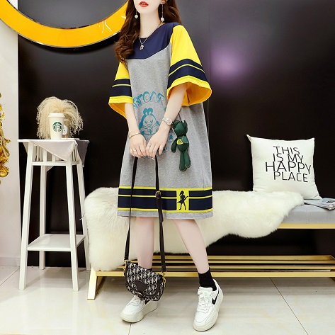 สาวตัวเล็กแต่งตัวกับเสื้อยืดตัวยาวสีเทาแขนเสื้อสีเหลืองแถบสีนํ้าเงินถือกระเป๋าสีดำ